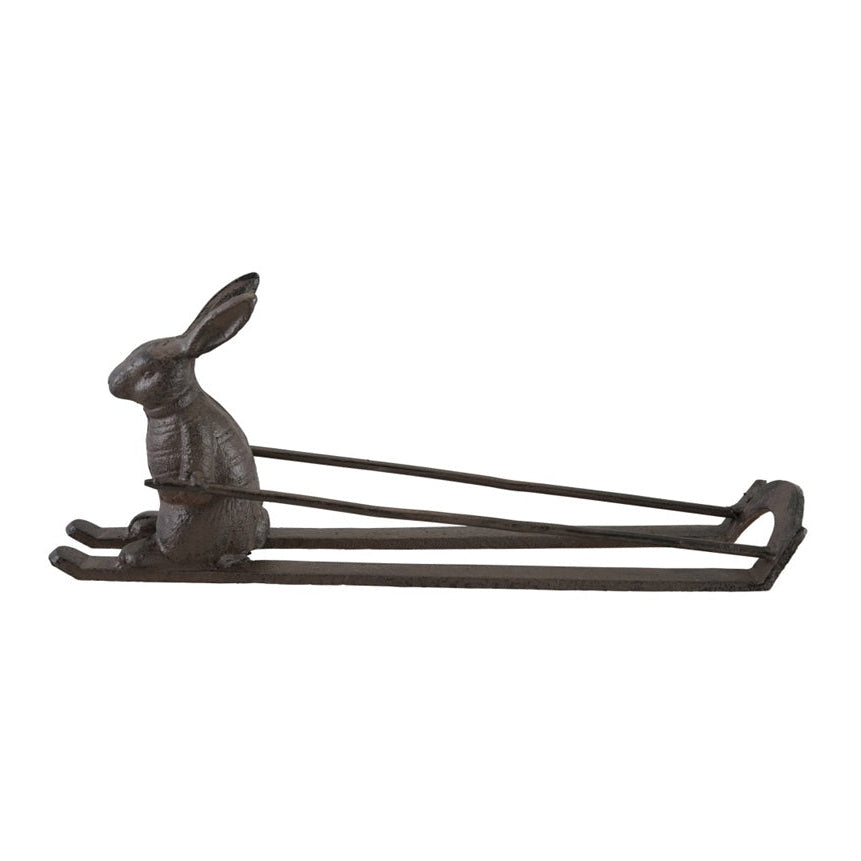 Side view of a rustic cast iron rabbit on skis bottle holder without a bottle.