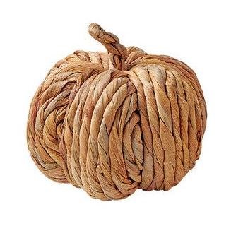 A woven pumpkin made from corn husk, with a rustic and natural appearance.