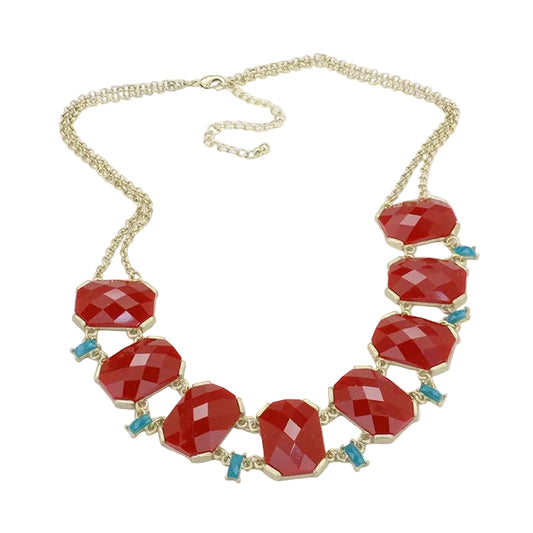 A gold-tone statement necklace featuring faceted red gemstone beads and small turquoise blue accent stones, displayed on a clean white background.