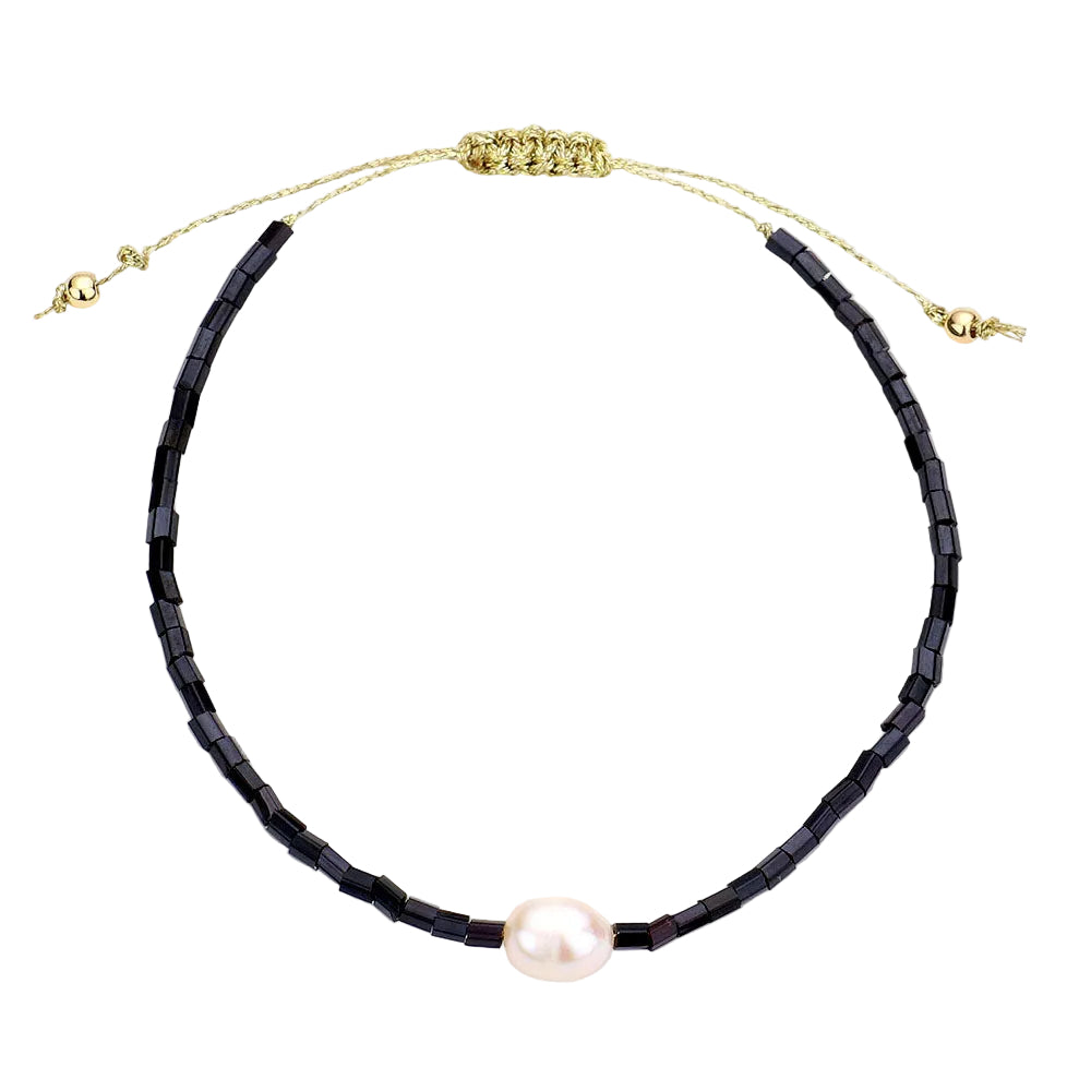 A black beaded bracelet with a freshwater pearl accent and an adjustable gold-colored clasp.