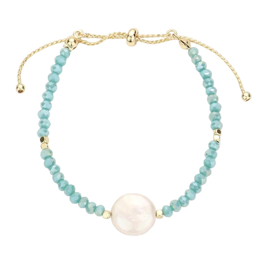 A turquoise beaded bracelet with a gold-colored pull tie and a large freshwater pearl accent in the center.