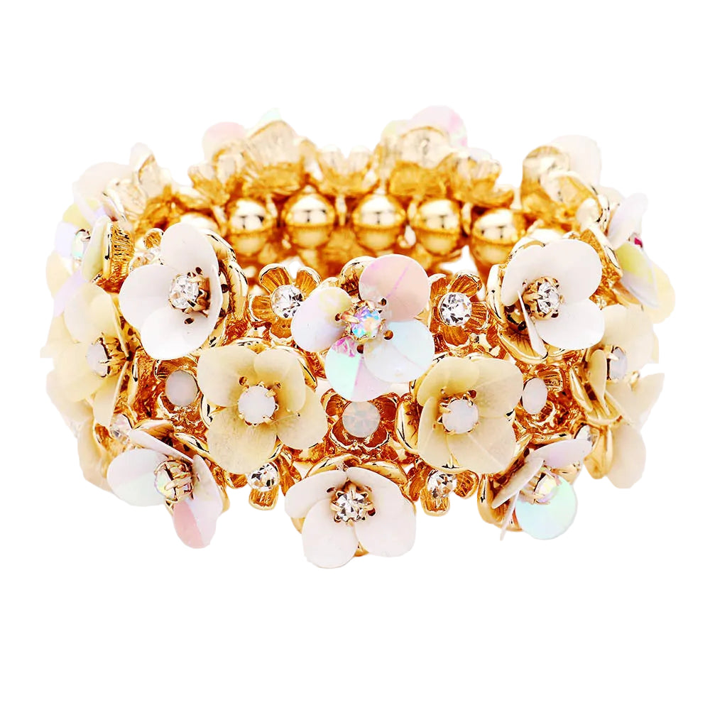 A stretchable bracelet with a gold-tone band and ivory-colored floral designs adorned with small clear crystals.