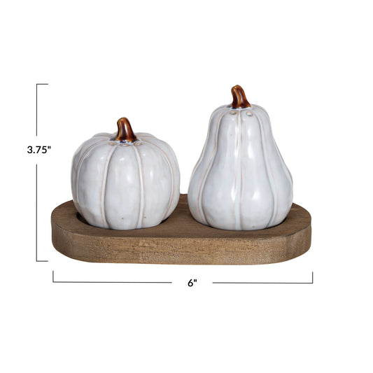 Two white ceramic pumpkins on a wooden stand with measurements indicated.