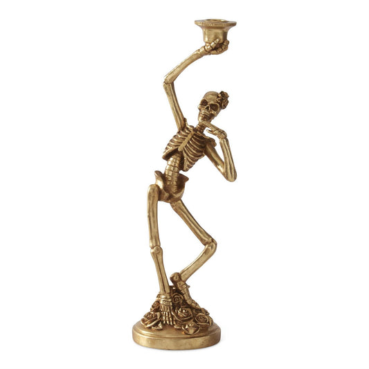 A decorative skeleton figurine in a gold finish, posed dynamically with one arm raised holding a bowl on a matching base, set against a plain white background.