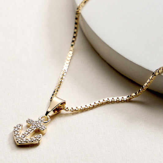 Gold necklace with an anchor pendant on a light background