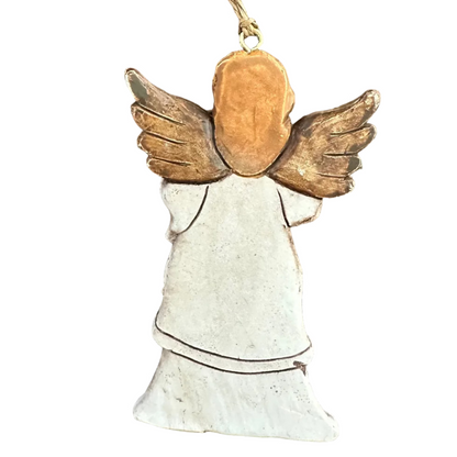 A rustic wooden angel Christmas ornament with brown wings, a light brown head, and a white dress, hanging on a white surface.