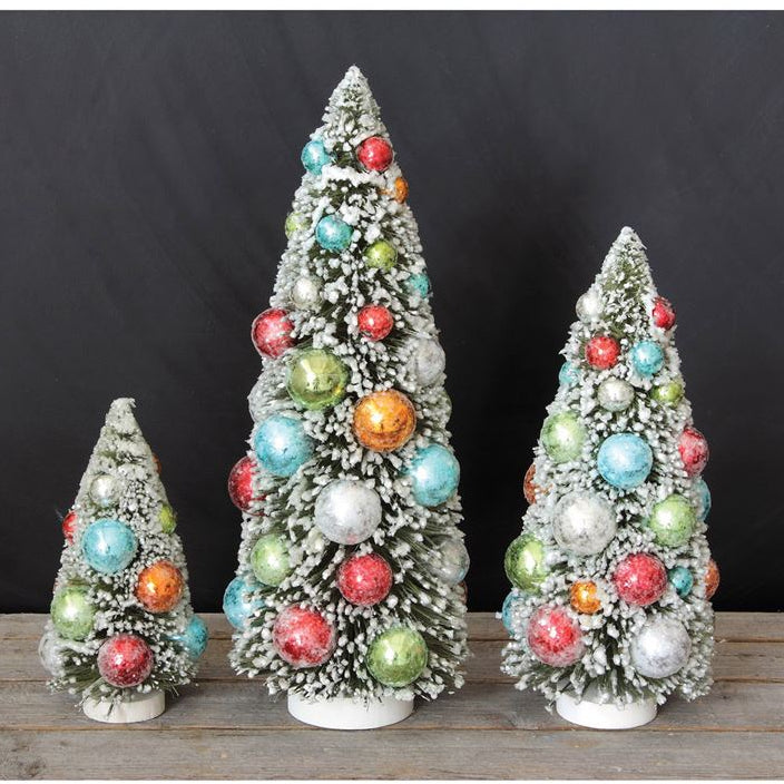 Three decorative Christmas trees with colorful ornaments on a wooden surface against a black background
