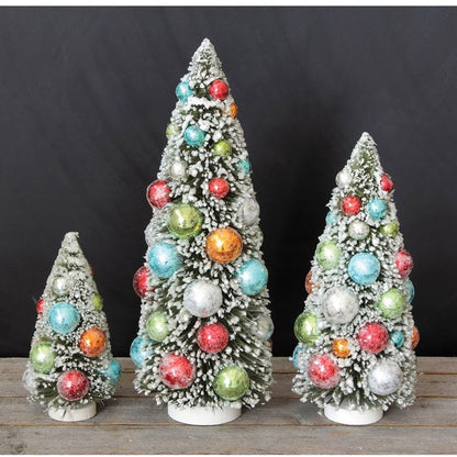 Three decorative Christmas trees with colorful ornaments on a wooden surface against a black background