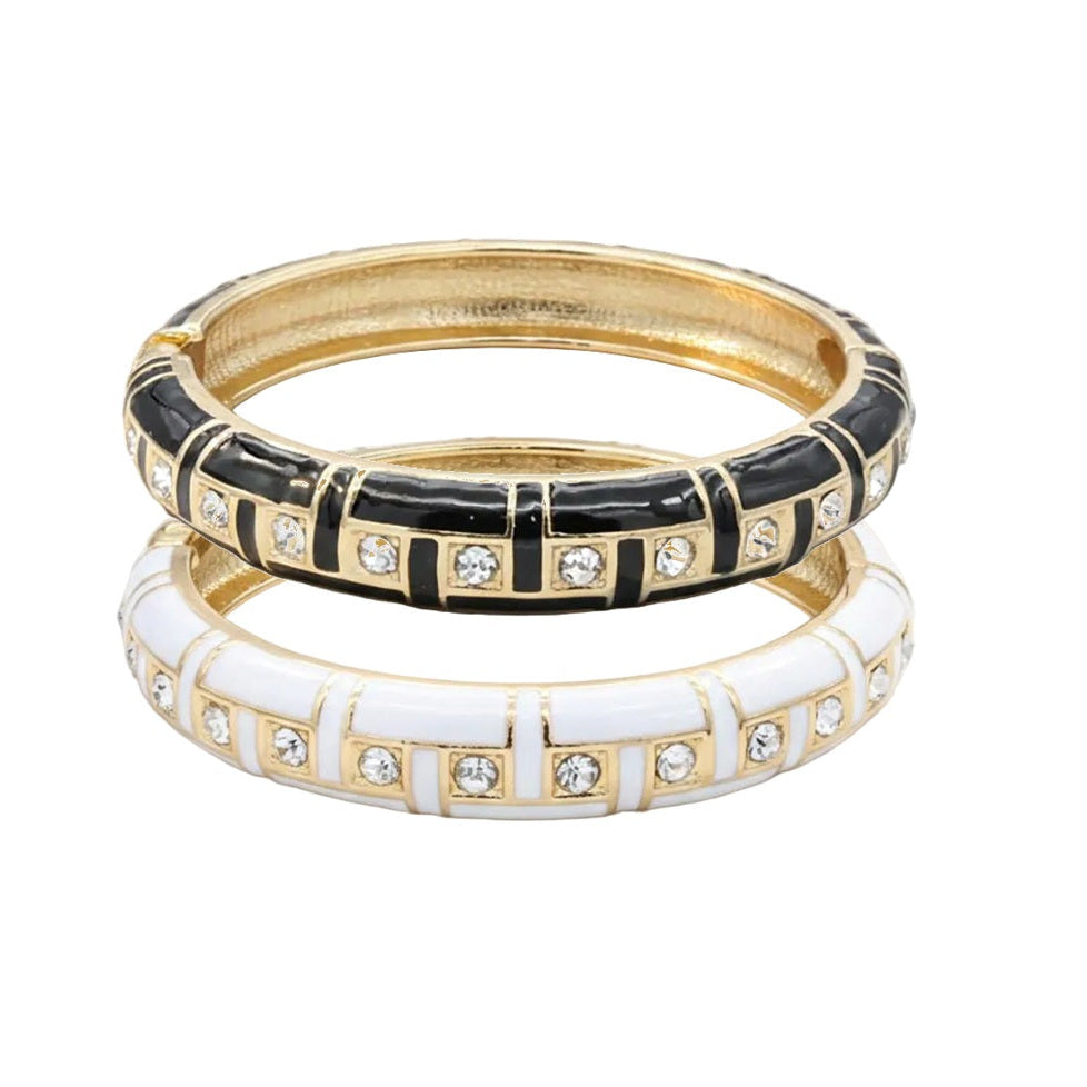Two gold bangles with black and white enamel designs on a white background
