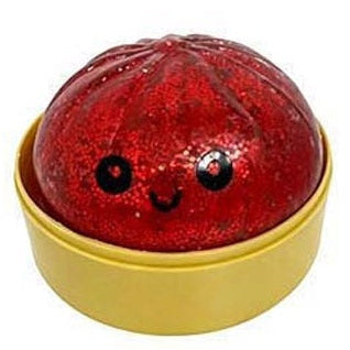Red glittery ball with black dots on a gold base against a white background