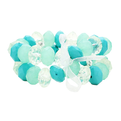 A set of two turquoise faceted lucite beaded stretch bracelets with a ribbon element in the center.