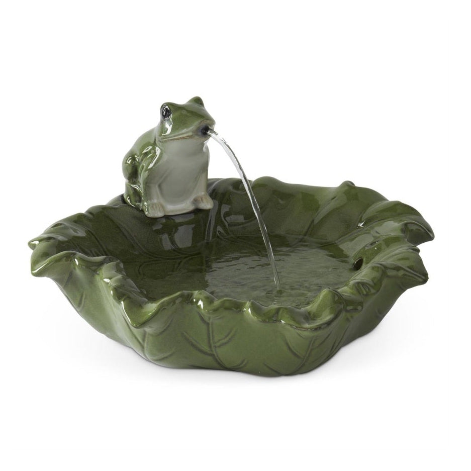 A green leaf-shaped fountain basin with a small frog figurine sitting on the rim, from which a stream of water flows into the basin, shown against a plain white background.
