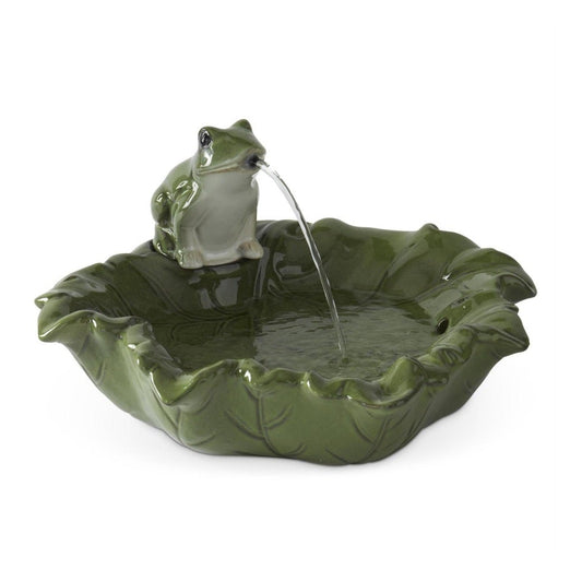 A green leaf-shaped fountain basin with a small frog figurine sitting on the rim, from which a stream of water flows into the basin, shown against a plain white background.