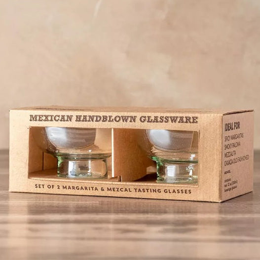 Set of 2 Mexican handblown glassware tasting glasses in a cardboard box on a wooden surface.