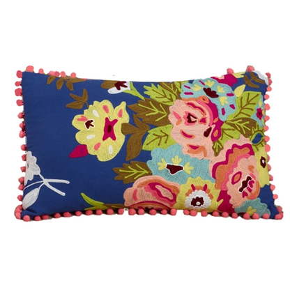 A rectangular decorative throw pillow with a vibrant floral pattern on a navy blue background, finished with pink pom-pom trim on all sides, shown against a plain white background.