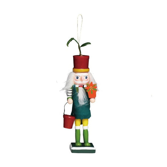 A small gardener nutcracker-style hanging ornament with a white beard, red hat, teal coat, green pants, and yellow boots, holding a red bucket and orange flower, on a plain white background.