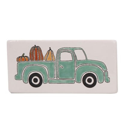 Ceramic rectangular box sign with a mint green truck carrying pumpkins in a field setting.