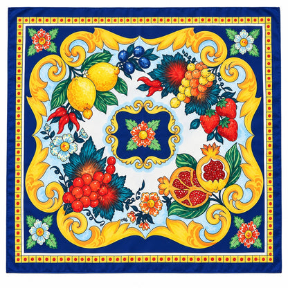 A square silk scarf featuring a vibrant Mediterranean-style print with lemons, strawberries, pomegranates, blueberries, and cherries framed by ornate gold scrollwork on a deep blue background.