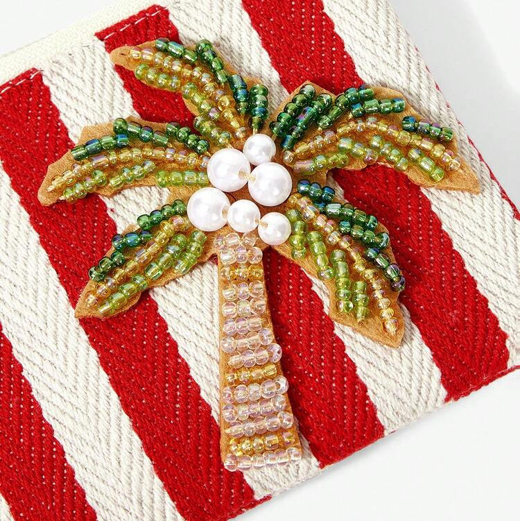 Red and white striped tropical coin purse featuring sparkling beaded palm tree with a red tassel, zipper closure and gold-tone keychain clip.