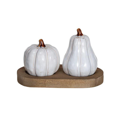 Two white stoneware salt and pepper shakers designed to look like pumpkins on a wooden tray.