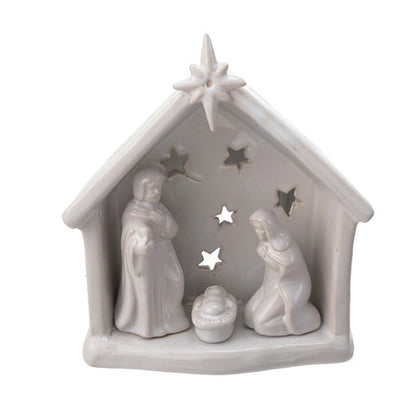 A small white ceramic  nativity scene figurine featuring Mary, Joseph, baby Jesus in a manger, and a star on the roof, set against a plain white background.