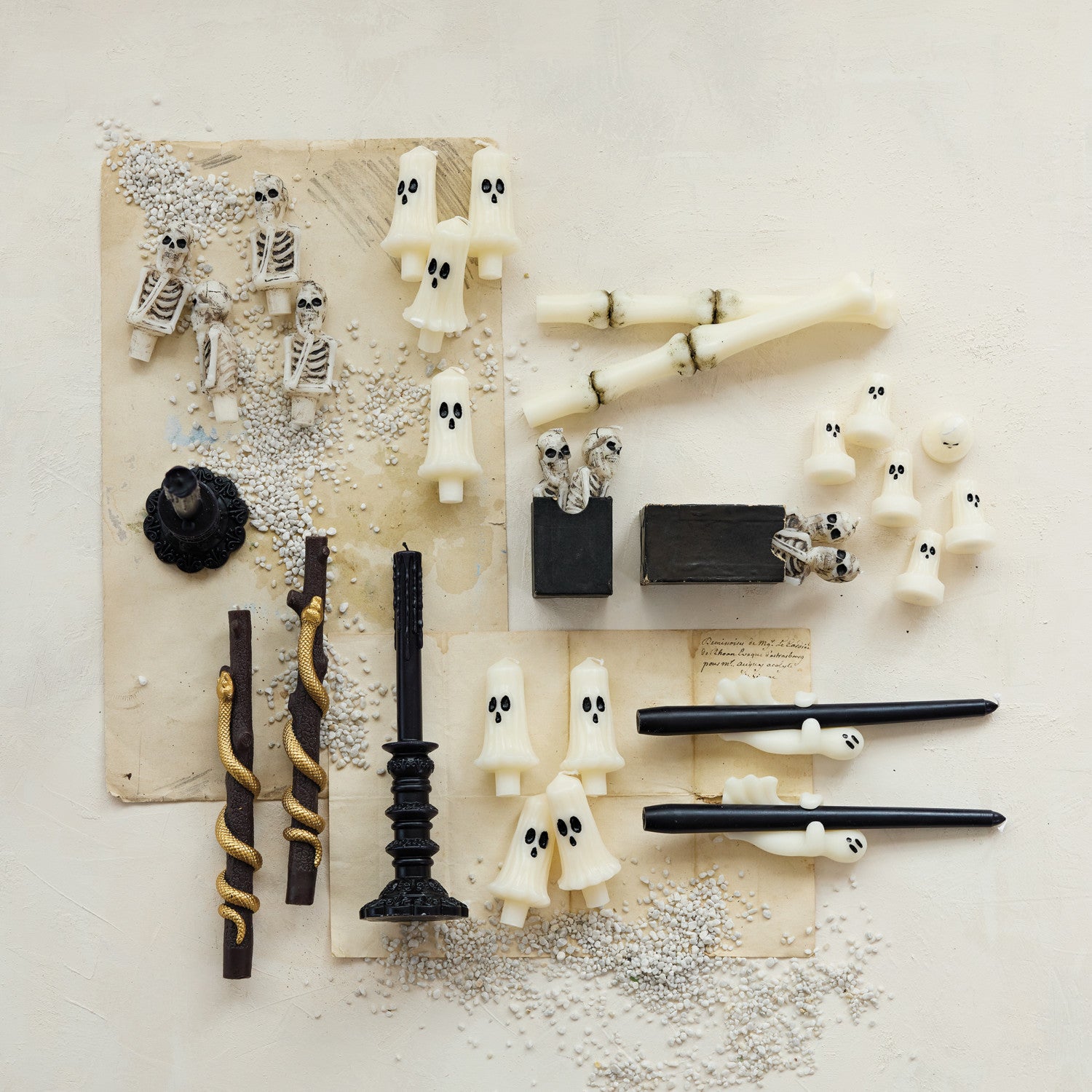Halloween-themed decorations including ghost figurines, candles, and bones on a textured surface.