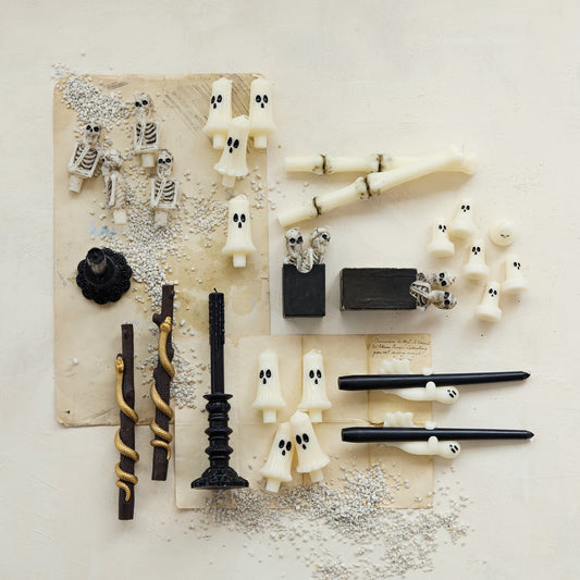 Halloween-themed decorations including ghost figurines, candles, and bones on a textured surface.