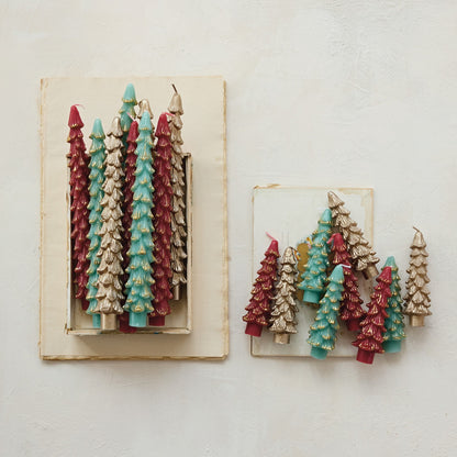 Decorative candles shaped like Christmas trees in red, green, and gold on a white background.